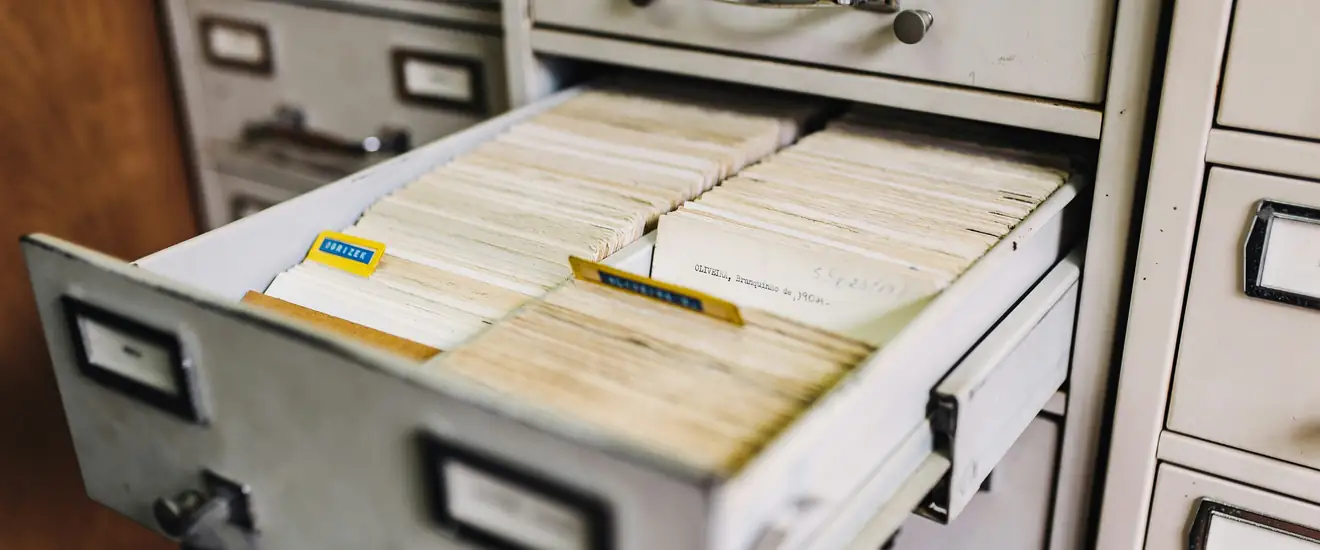 An open metal filing cabinet drawer packed with index cards